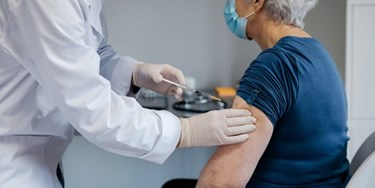 Woman in chair wearing mask receiving vaccine