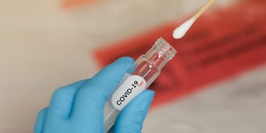 Close up of hand in surgical gloves holding a Covid-19 testing kit
