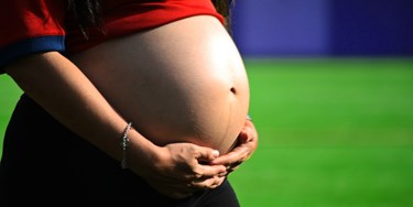 Close Up Of Woman With Hands On Her Pregnancy Bump