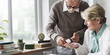Man helping woman with medication
