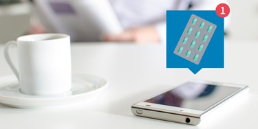 Phone on table with a beverage, notification appears on phone
