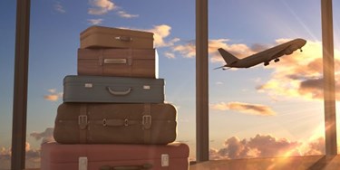 Suitcases piled up with plane taking off in distance