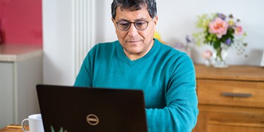 Pharmacy2U patient Samir using the website on a laptop in his dining room