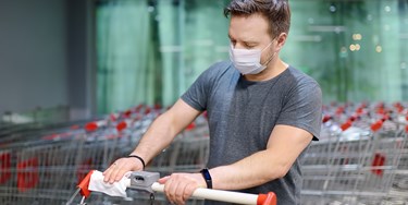 Man Sanitising Trolley Handle