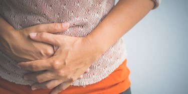 Woman Clasping Her Abdomen In Discomfort